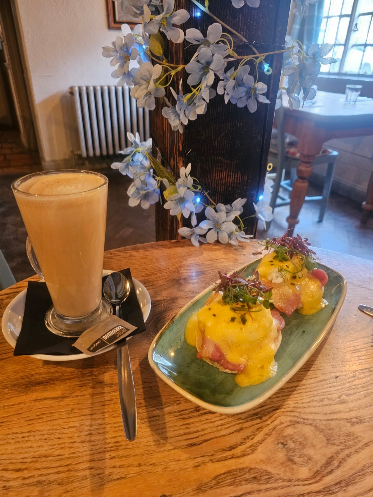 A latte and Eggs Benedict served on a wooden table at The Ilchester Arms